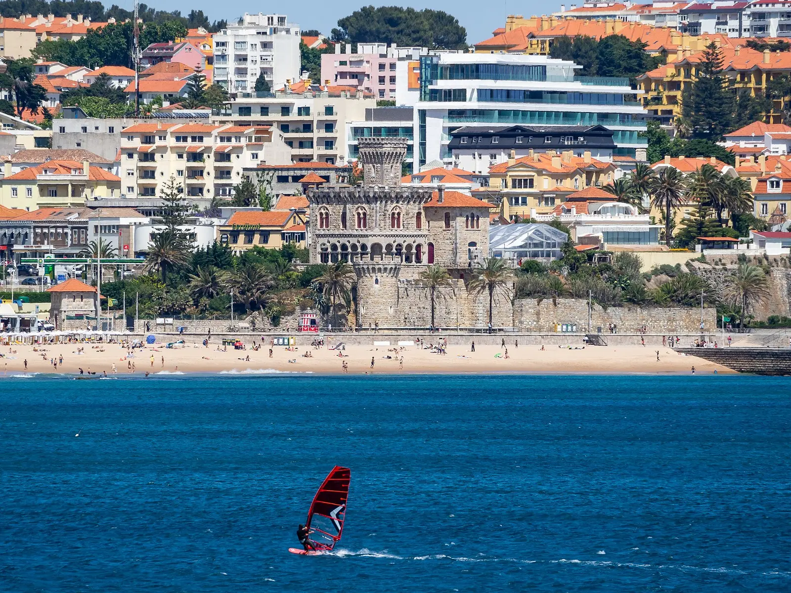 Windsurfer on blue water in Cascais Bay with the town behind